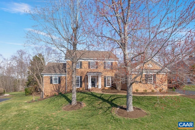 colonial home with a front yard and brick siding