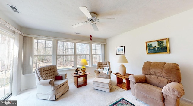 living area featuring visible vents, carpet floors, a textured ceiling, and a ceiling fan