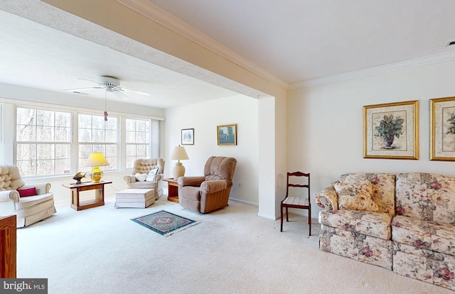 carpeted living room with baseboards, ornamental molding, and a ceiling fan