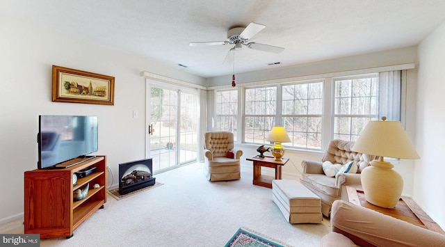 living area featuring carpet flooring, a healthy amount of sunlight, a ceiling fan, and visible vents