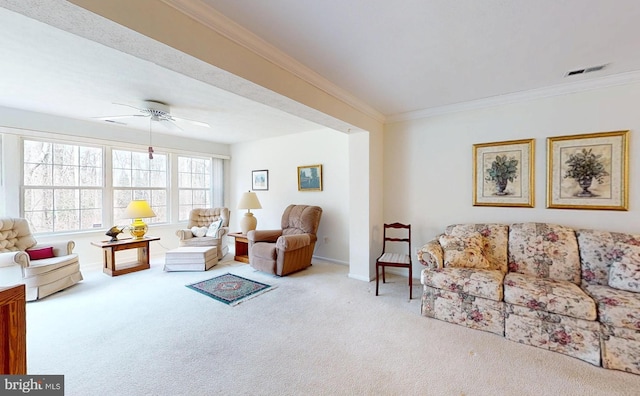 living area with visible vents, ornamental molding, carpet floors, baseboards, and ceiling fan