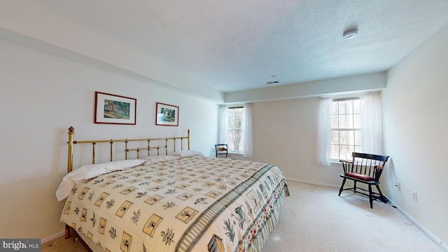 bedroom with visible vents, light colored carpet, a textured ceiling, and baseboards