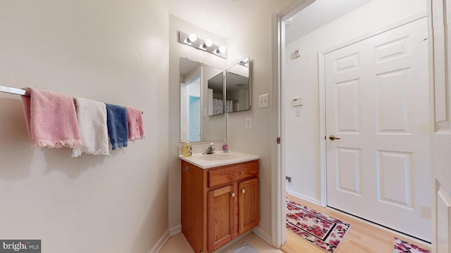 bathroom with vanity, baseboards, and wood finished floors