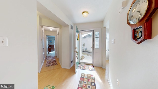 foyer with wood finished floors, visible vents, and baseboards