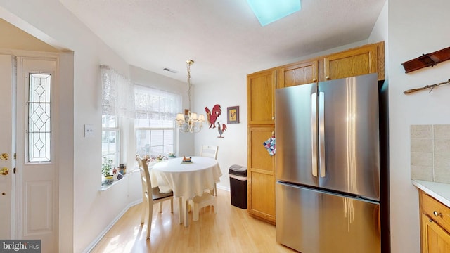 kitchen featuring visible vents, a chandelier, light countertops, light wood-style flooring, and freestanding refrigerator