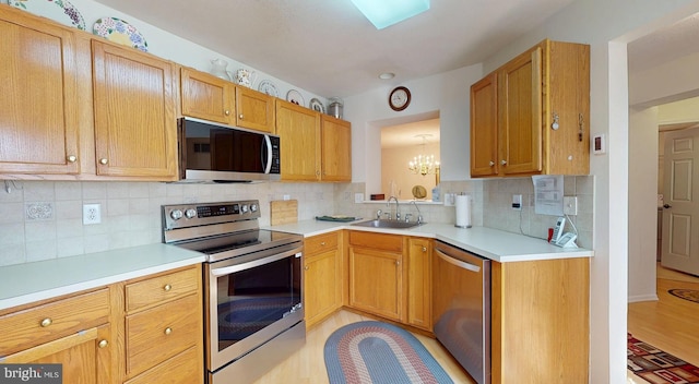 kitchen featuring a notable chandelier, appliances with stainless steel finishes, light countertops, and a sink