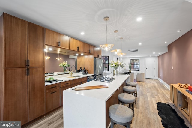 kitchen featuring a kitchen bar, a sink, a center island, stainless steel appliances, and light countertops