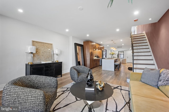 living room with recessed lighting, baseboards, light wood-style floors, and stairs