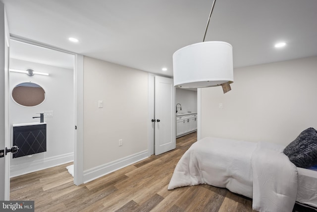 bedroom with light wood finished floors, baseboards, and a sink