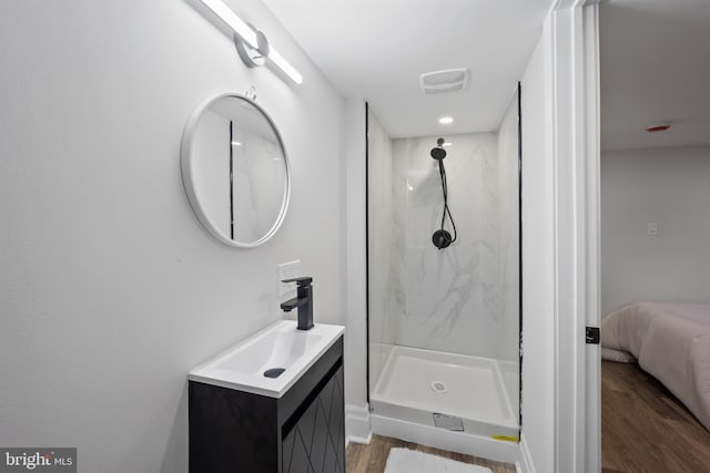 ensuite bathroom featuring vanity, wood finished floors, visible vents, and a marble finish shower