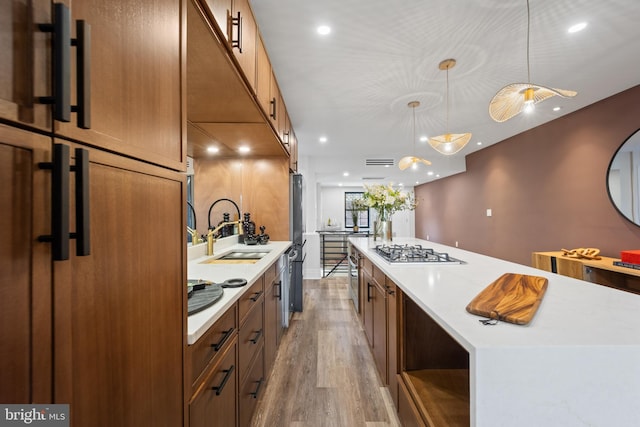 kitchen featuring a sink, stainless steel appliances, a large island, and light countertops