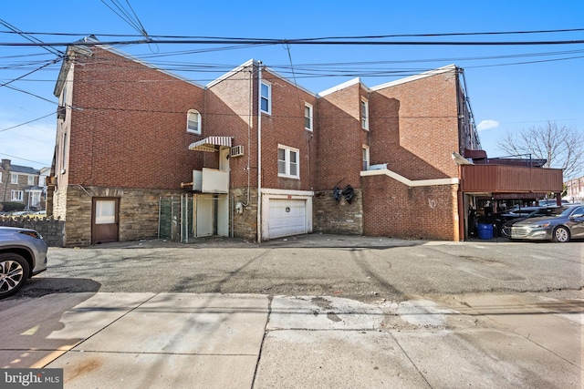 view of property exterior with brick siding, an attached garage, and driveway