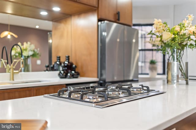 kitchen with brown cabinets, a sink, recessed lighting, stainless steel appliances, and light countertops