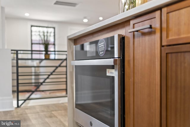 interior space featuring visible vents, light wood-type flooring, recessed lighting, brown cabinetry, and stainless steel oven