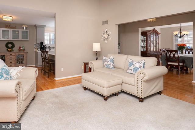 living room featuring visible vents, baseboards, an inviting chandelier, and wood finished floors