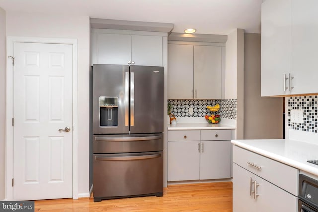 kitchen featuring tasteful backsplash, oven, light countertops, gray cabinets, and stainless steel refrigerator with ice dispenser