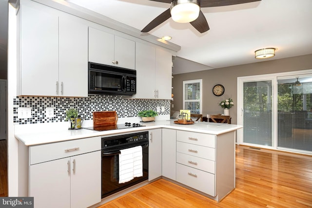 kitchen featuring a peninsula, black appliances, light countertops, light wood-style floors, and a wealth of natural light