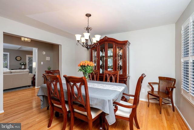 dining space with light wood-style floors, baseboards, a wealth of natural light, and a chandelier