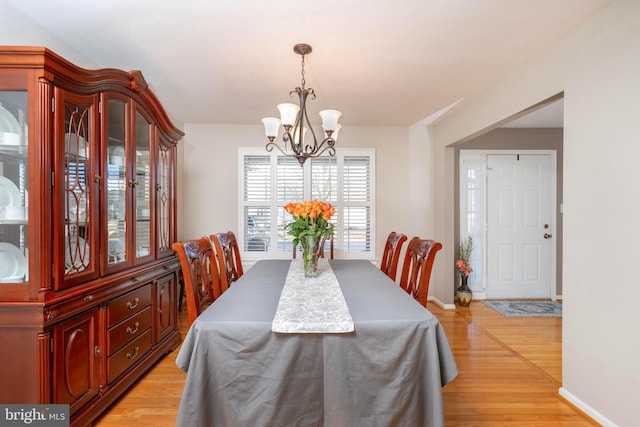 dining space with baseboards, an inviting chandelier, and light wood finished floors