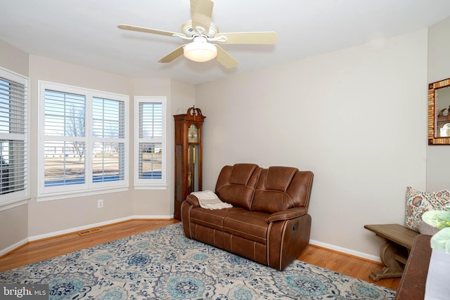 living area featuring visible vents, a ceiling fan, baseboards, and wood finished floors