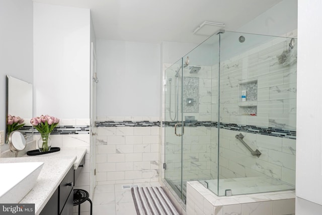 bathroom with tile walls, a shower stall, wainscoting, and vanity