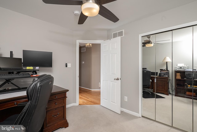 home office with visible vents, light colored carpet, baseboards, and a ceiling fan