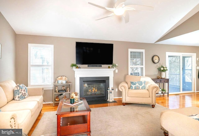 living room with vaulted ceiling, a fireplace with flush hearth, and wood finished floors