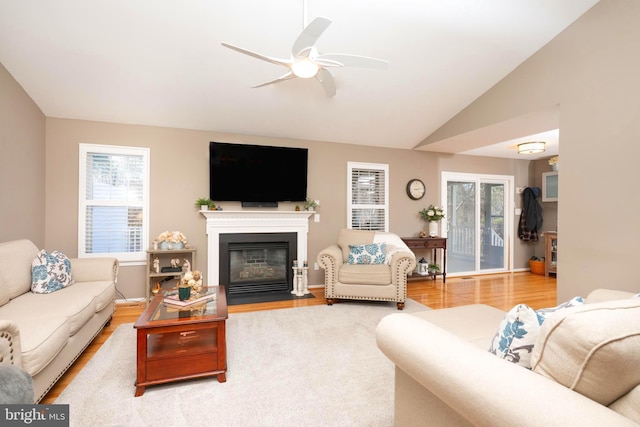 living area featuring plenty of natural light, a fireplace with flush hearth, lofted ceiling, and wood finished floors