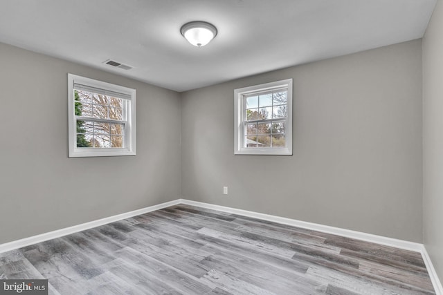 spare room with visible vents, baseboards, and wood finished floors