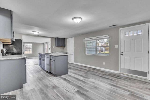 kitchen with visible vents, gray cabinetry, baseboards, light wood-style floors, and a sink