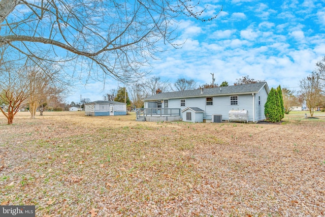 back of property featuring a wooden deck, a yard, central AC, a chimney, and an outdoor structure