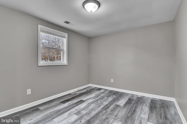 empty room featuring visible vents, baseboards, and wood finished floors