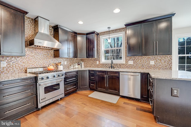 kitchen featuring a sink, wall chimney exhaust hood, light wood finished floors, and stainless steel appliances