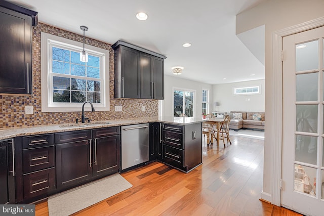 kitchen featuring open floor plan, dishwasher, light wood-type flooring, and a sink