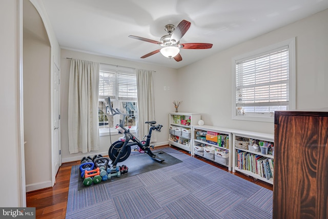 exercise room with ceiling fan, baseboards, and wood finished floors