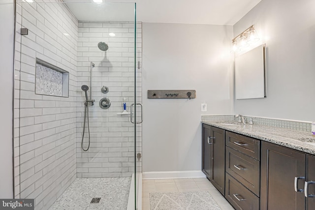 full bathroom with vanity, a shower stall, baseboards, and tile patterned floors