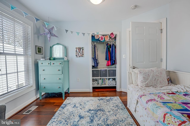 bedroom featuring visible vents, a walk in closet, wood finished floors, a closet, and baseboards