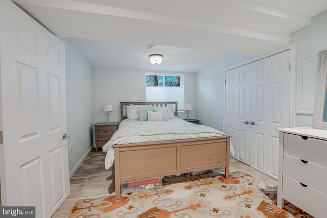 bedroom with a closet, light wood-type flooring, and baseboards