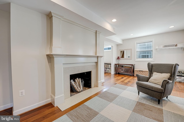 sitting room with recessed lighting, wood finished floors, baseboards, and a premium fireplace