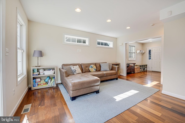 living area with recessed lighting, visible vents, baseboards, and wood finished floors