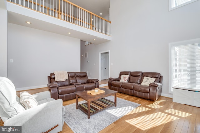 living area with recessed lighting, a high ceiling, baseboards, and hardwood / wood-style flooring