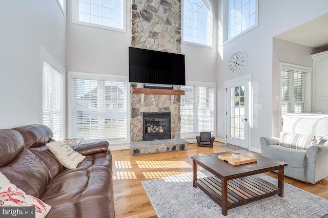 living room with baseboards, plenty of natural light, a stone fireplace, and wood finished floors