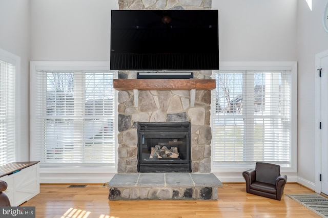 interior details featuring visible vents, baseboards, a stone fireplace, and wood finished floors