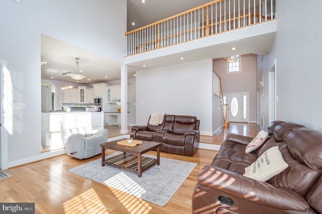 living room featuring light wood-style floors, baseboards, and a towering ceiling