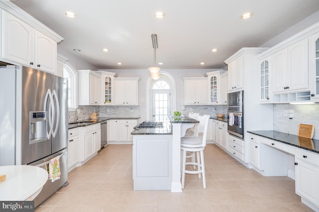 kitchen with appliances with stainless steel finishes, white cabinetry, a kitchen bar, and a sink