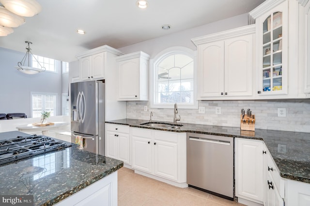 kitchen featuring a sink, decorative backsplash, glass insert cabinets, appliances with stainless steel finishes, and white cabinetry