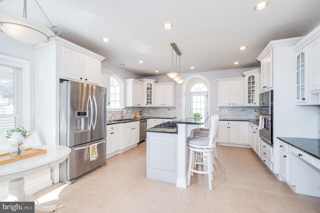 kitchen with a sink, a kitchen bar, appliances with stainless steel finishes, and white cabinets