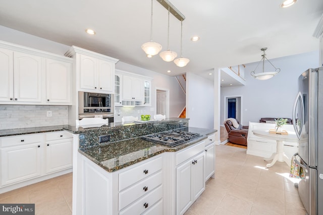 kitchen with a kitchen island, built in microwave, black gas cooktop, dark stone counters, and freestanding refrigerator