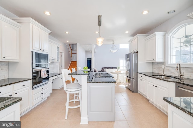 kitchen with a sink, a kitchen breakfast bar, white cabinets, and stainless steel appliances