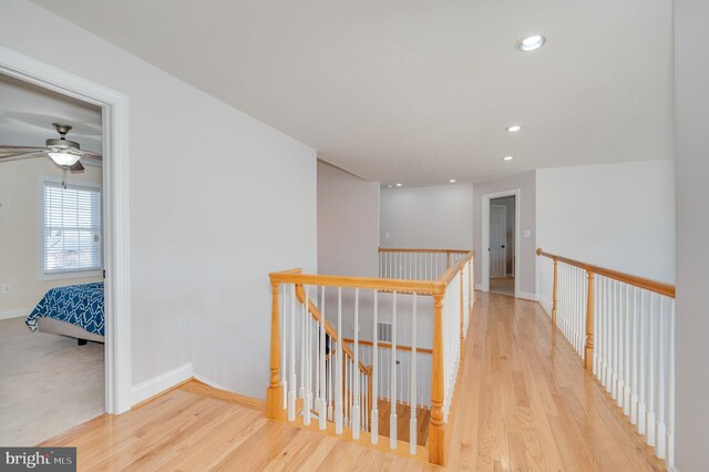 hallway with an upstairs landing, recessed lighting, baseboards, and wood finished floors